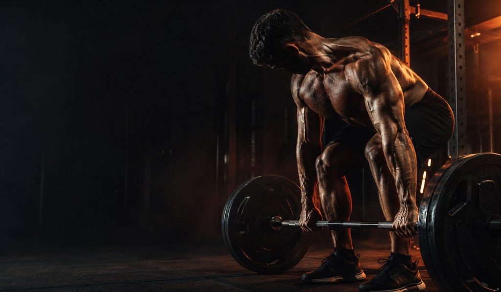 Athlete performing a heavy deadlift in a dark gym